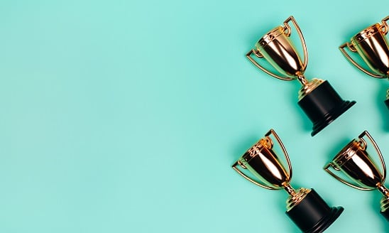 Frame made of gold trophies on pastel blue background