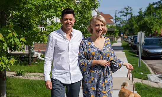 Hospitality business alumni Kyle Welch and Alex Clark walk down a sidewalk on a sunny day.