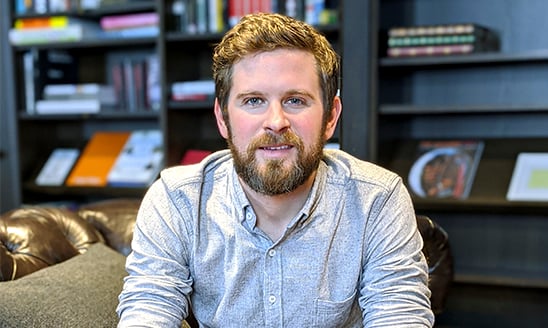 MSU alumnus and creative director at Google Creative Lab Jesse Juriga sits in a leather chair in an office with a bookshelf in the background.