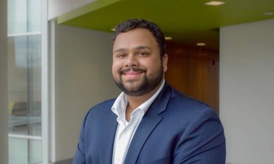 A professional headshot of MSU finance student Abhishek Tekumulla in a bright, open office space.