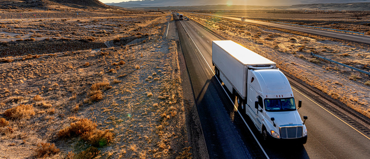Semi truck driving down a highway at dusk