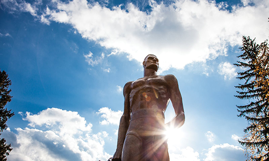The Spartan statue against a bright blue sky