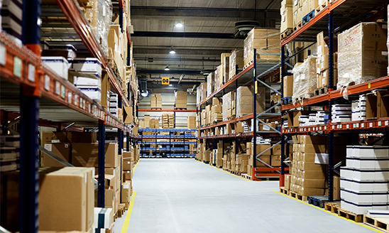 Empty warehouse, view down the aisle with shelves and boxes.