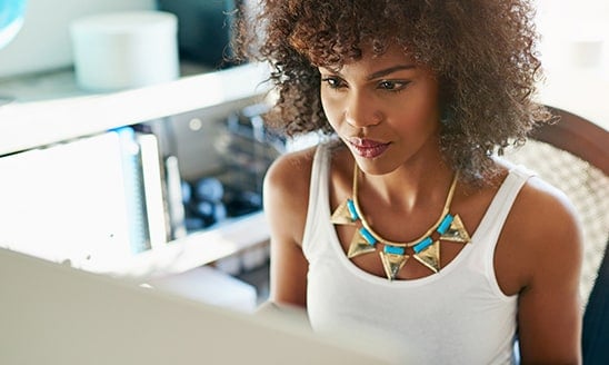A Black woman works from home at her desktop computer.