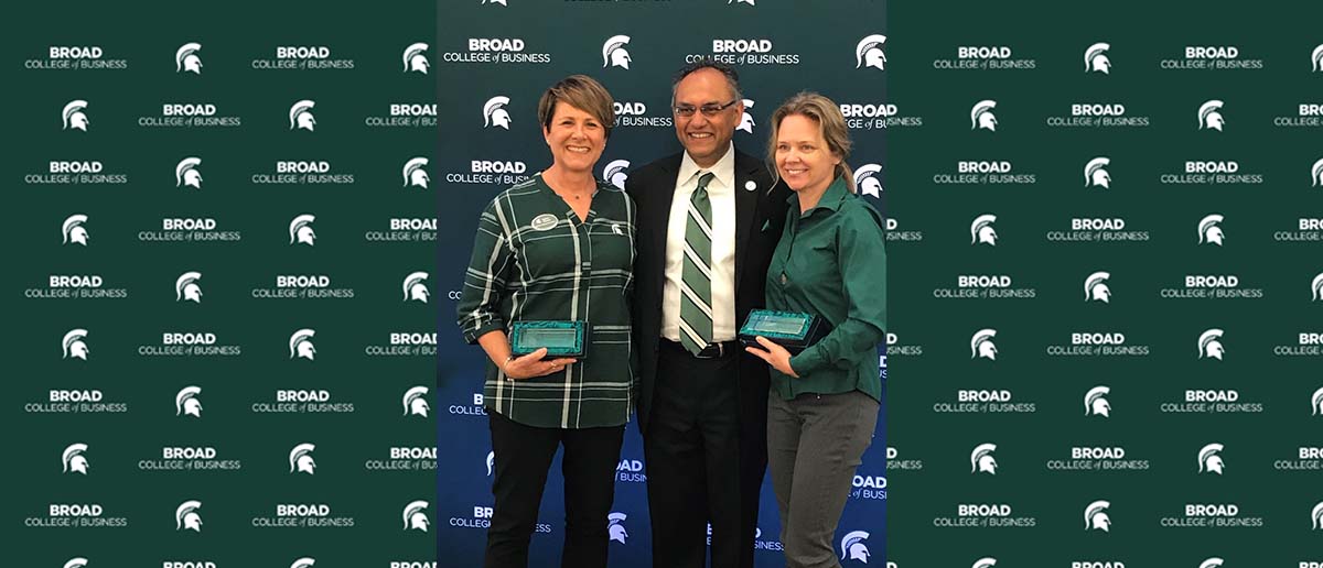 (From left) Lynne Zelewski, Sanjay Gupta, and Lori Jacskon stand in front of a Broad College of Business step-and-repeat banner while Lynne and Lori hold their awards