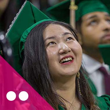 A student in her commencement cap and gown smiles