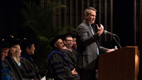Ray Scott, president of Lear Corporation, speaks at the Executive MBA commencement ceremony, with the platform party visible behind him