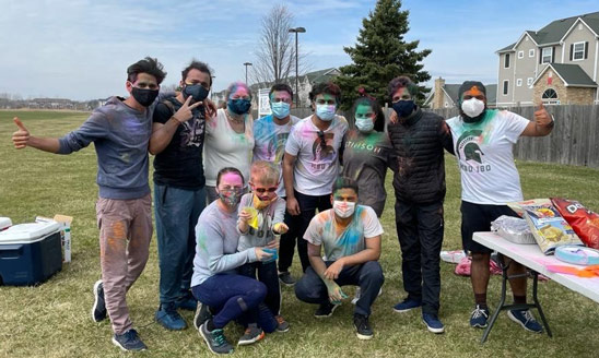 A group of students posing to show the brightly colored powder on their clothing for Holi celebrations