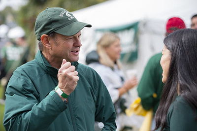Two people conversing with a crowd in the background at a 2018 homecoming tailgate event