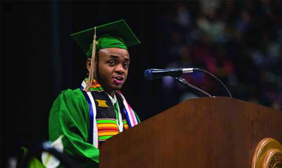 Lamont Davis (B.A. Hospitality Business '19) dressed in cap and gown, speaking to the class of 2019 at the fall commencement ceremony.