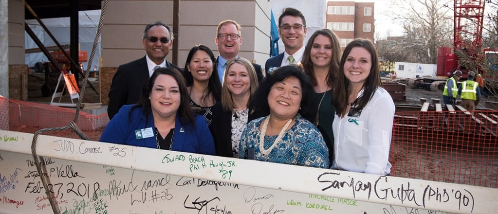 Dean Gupta and the Development team in front of the signed steel beam at the topping off ceremony