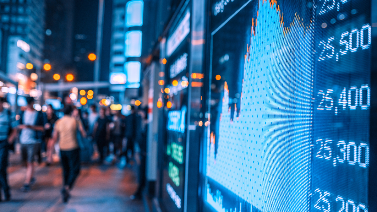 Stock price movements on a screen facing a sidewalk at night