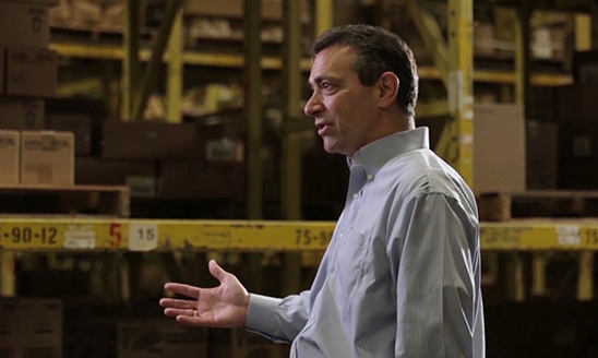 Dennis Eidson (B.A. Business Administration ’76), Chairman of the Board and interim President and CEO of SpartanNash, pictured speaking inside a warehouse. 