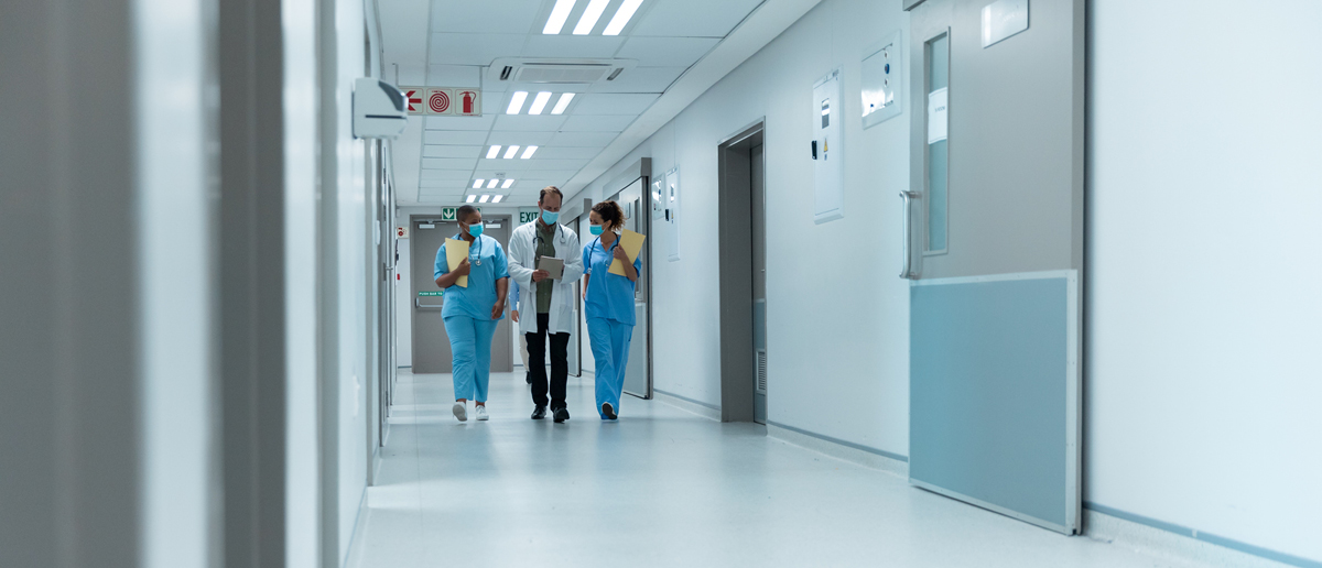Three health care workers walk down a hospital hallway
