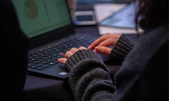 A close-up image of a woman typing on a laptop computer.