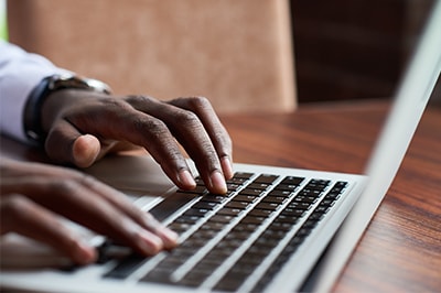 Close up image of man typing on laptop.